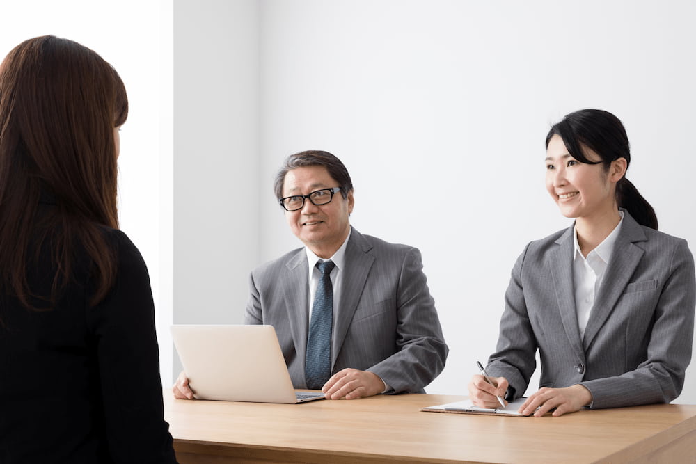 採用面接で書類を確認する面接官と求職者。契約内容の確認が重要