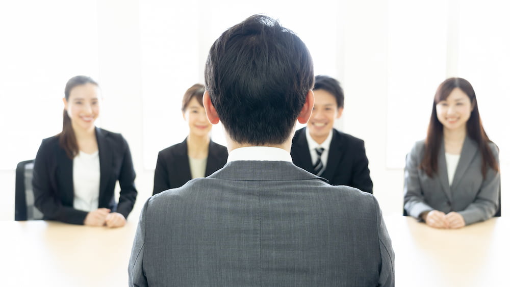 採用面接の様子。求職者の背中越しに複数の面接官が向き合っている