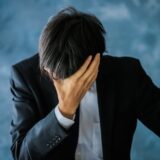 ストレスを抱えて頭を抱えるビジネスパーソン。精神障害の労災認定が過去最多を記録している
