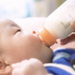 哺乳瓶でミルクを飲む赤ちゃん。出生後休業支援給付金・育児時短就業給付金の対象となる育児のイメージ