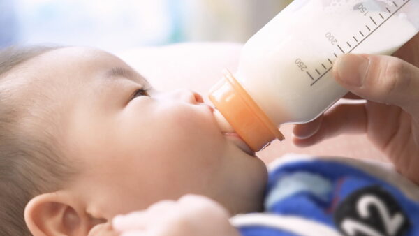 哺乳瓶でミルクを飲む赤ちゃん。出生後休業支援給付金・育児時短就業給付金の対象となる育児のイメージ