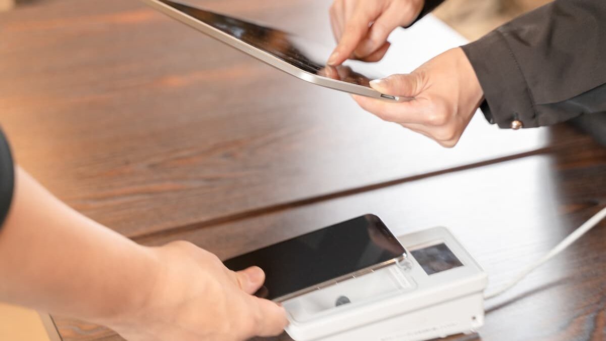 タブレットとスマホ決済端末を操作する手元。賃金のデジタル払い・キャッシュレス決済のイメージ