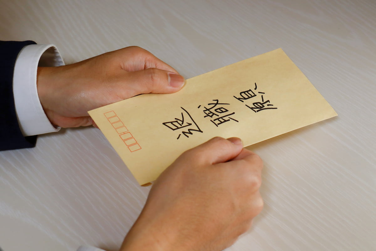 退職届と青いペン。欠員発生時の業務引継ぎや組織対応を考えるイメージ