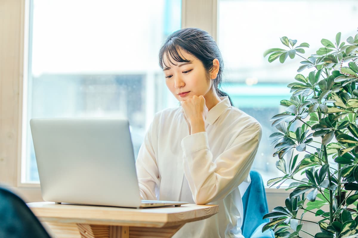 オフィスでパソコンに向かい考え込む女性社員。職場での悩みや尊厳について考えるイメージ