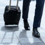 新幹線のホームでスーツケースを持つ出張中のビジネスパーソン