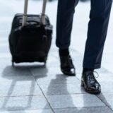 新幹線のホームでスーツケースを持つ出張中のビジネスパーソン