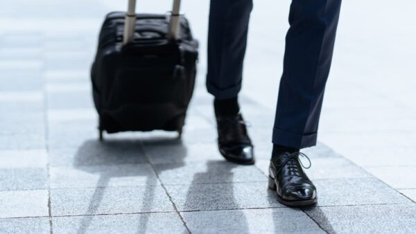 新幹線のホームでスーツケースを持つ出張中のビジネスパーソン