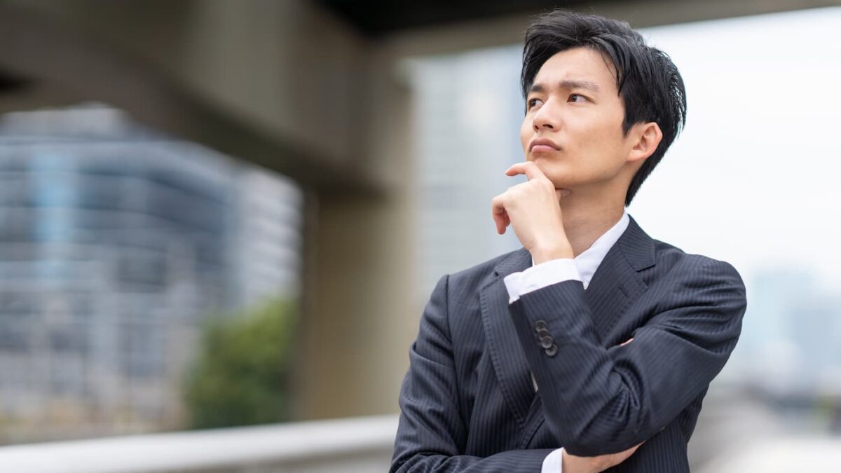顎に手を当て営業ノルマについて思い悩むビジネスマン