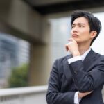 顎に手を当て営業ノルマについて思い悩むビジネスマン