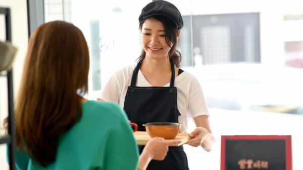 笑顔で接客研修を受ける大学生アルバイトスタッフ