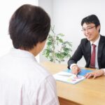 資料を使って年金制度の説明を受けるシニア夫婦と社労士