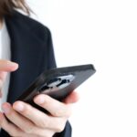 スマートフォンを操作するスーツ姿のビジネスパーソンの手元