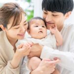 赤ちゃんを抱く両親。2026年8月1日から育児休業給付の手続きが変わることをイメージした写真。