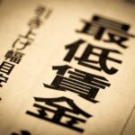 「最低賃金」「引き上げ幅目安」の見出しが並ぶ新聞紙面（令和8年度最低賃金改定のイメージ）