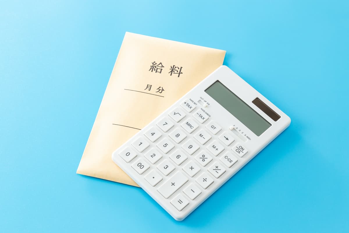 「給料」と書かれた封筒と電卓（最低賃金を下回らないか賃金を確認するイメージ）