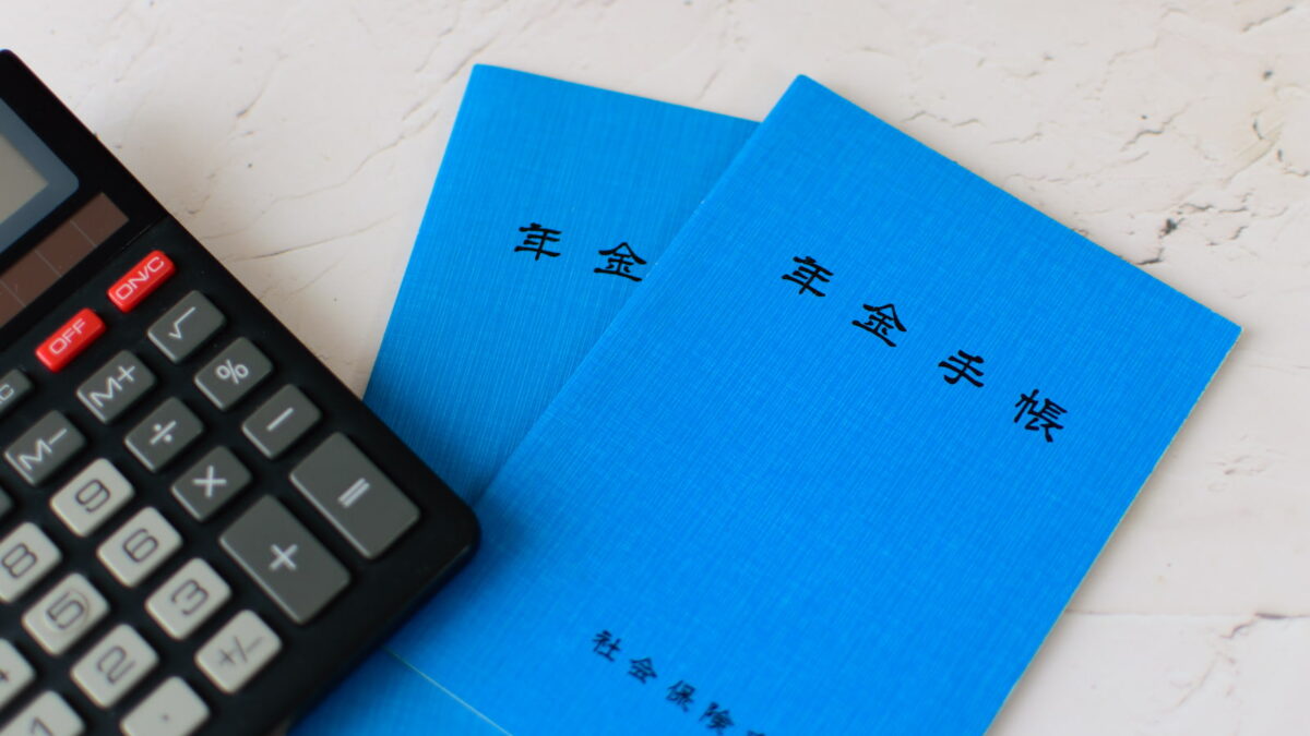 2冊の年金手帳と電卓(社会保険の適用拡大と保険料計算のイメージ)