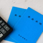 2冊の年金手帳と電卓（社会保険の適用拡大と保険料計算のイメージ）